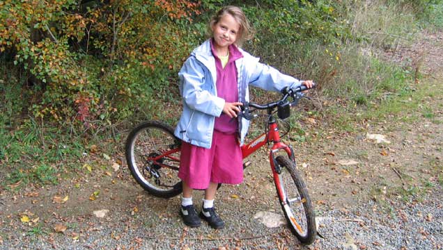 Lena arrive en vélo à l'école des Clos, elle sort de la forêt !